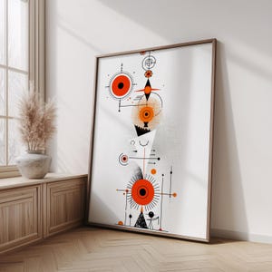 May include: A framed wall art print featuring a vertical arrangement of geometric shapes, including orange circles, black lines, and dotted textures on a white background. The composition includes stylized sun-like motifs and abstract symbols.