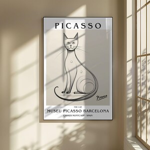 May include: A framed art print featuring a Picasso sketch of a cat. The artwork is in black and white, with the name "Picasso" at the top and the text "Museu Picasso Barcelona" at the bottom. The cat is depicted with long lines and a minimalist style.
