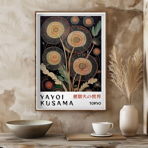 May include: A framed art print featuring a floral design with circular shapes in shades of yellow, orange, and green against a black background. The print includes the text "YAYOI KUSAMA" and Japanese characters, with "TOKYO" below.