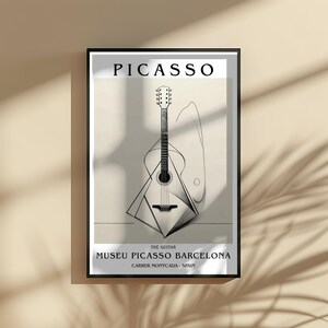 Puede incluir: Impresi&oacute;n art&iacute;stica enmarcada con un dibujo lineal en blanco y negro de una guitarra. La impresi&oacute;n incluye el nombre "PICASSO" en la parte superior y "MUSEU PICASSO BARCELONA" en la parte inferior, con el texto "THE GUITAR" en el medio.