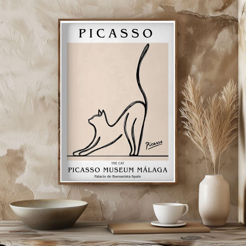 Puede incluir: Un cuadro enmarcado con un dibujo lineal negro de un gato estir&aacute;ndose sobre un fondo beige. El cuadro incluye el nombre "Picasso" en la parte superior y "Picasso Museum M&aacute;laga" en la parte inferior, con la firma del artista.