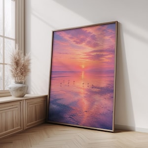 Peut inclure: Une impression d'art murale encadrée rectangulaire représentant un coucher de soleil sur une plage calme avec des teintes roses et orange dans le ciel et l'eau. La scène inclut de petites silhouettes d'oiseaux sur le sable mouillé reflétant le soleil.