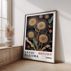 May include: A framed art print featuring a stylized floral design with a black background. The artwork includes large, circular flower-like shapes in shades of beige and orange, with green leaves. The print includes the text "YAYOI KUSAMA" and Japanese characters.