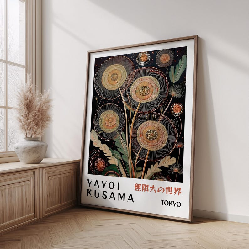 May include: A framed art print featuring a stylized floral design with a black background. The artwork includes large, circular flower-like shapes in shades of beige and orange, with green leaves. The print includes the text "YAYOI KUSAMA" and Japanese characters.