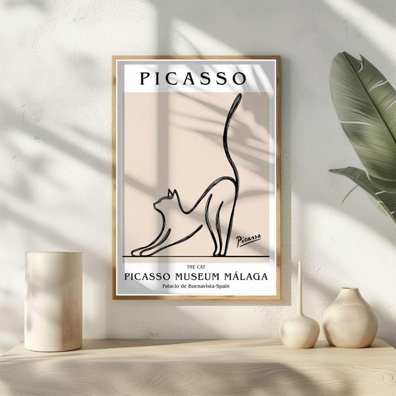 Puede incluir: Una impresi&oacute;n art&iacute;stica enmarcada con un dibujo lineal minimalista de un gato estir&aacute;ndose. La impresi&oacute;n incluye el nombre "PICASSO" en la parte superior, con "THE CAT" y "PICASSO MUSEUM M&Aacute;LAGA" debajo. La obra de arte est&aacute; en un marco dorado.
