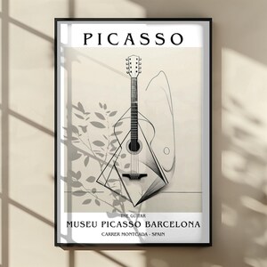 Puede incluir: L&aacute;mina enmarcada con una ilustraci&oacute;n de guitarra de Picasso. La obra de arte incluye el texto "PICASSO" en la parte superior, y "THE GUITAR" y "MUSEU PICASSO BARCELONA, CARRER MONTCADA - SPAIN" en la parte inferior. La guitarra est&aacute; representada en un estilo minimalista.