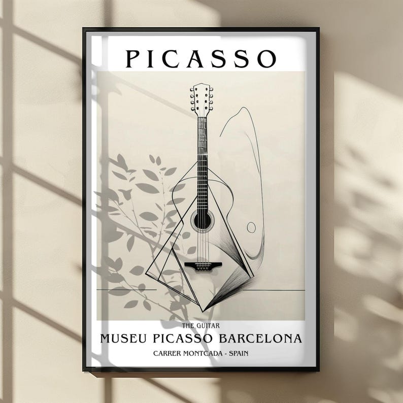 Puede incluir: L&aacute;mina enmarcada con una ilustraci&oacute;n de guitarra de Picasso. La obra de arte incluye el texto "PICASSO" en la parte superior, y "THE GUITAR" y "MUSEU PICASSO BARCELONA, CARRER MONTCADA - SPAIN" en la parte inferior. La guitarra est&aacute; representada en un estilo minimalista.