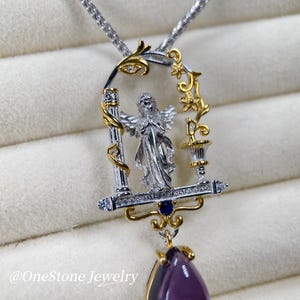 May include: A silver and gold pendant necklace with an angel design within a decorative frame. The pendant has a teardrop-shaped, deep purple gemstone. The necklace chain is silver. The text "@OneStone Jewelry" is visible.