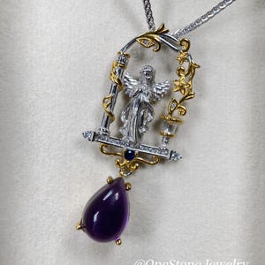 May include: Silver and gold-tone pendant necklace featuring an angel figure within a decorative frame. The pendant includes a teardrop-shaped, deep purple amethyst gemstone. The necklace has a silver chain.