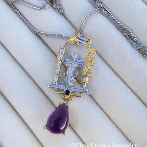 May include: A silver and gold pendant necklace with an angel design. The pendant has a teardrop-shaped purple gemstone and is suspended from a fine chain. The necklace features the text "@OneStone Jewelry".