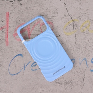 May include: A pale blue phone case with a distinctive design. The case features a circular pattern and a curved handle. The words "DARE TO BE DIFFERENT" are printed on the bottom. The case is designed to protect the phone.