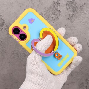 May include: A yellow and blue phone case with a heart-shaped ring holder. The case has a light blue background with a purple cloud graphic. The ring holder is purple, yellow, and orange. The text "GGSHARE" is visible.