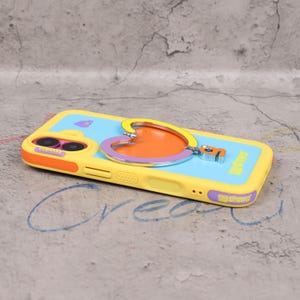 May include: A yellow and blue phone case with a heart-shaped design. The case has an orange and purple heart-shaped accent with a silver outline. The case has the word "GGshine" printed on the bottom. The phone case has a camera cutout.