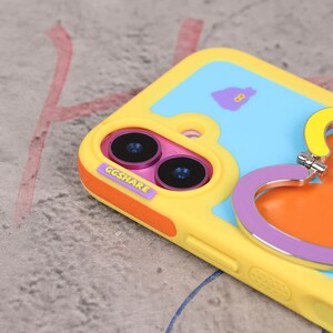 May include: A yellow, blue, and orange phone case with a heart-shaped grip. The case has a playful design with the text "GGSHARE" and a cartoon graphic. The camera lenses are visible.