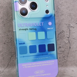 May include: A clear phone case with a blue and purple gradient design. The case features text that reads "ULTRAVIOLET strength testing" and a series of color-coded squares indicating UV strength. The case also has the text "Pay attention to sunscreen".