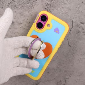 May include: A yellow, blue, and orange phone case with a heart design and a purple and silver phone ring. The case has the text "GGSHARE" on the side.