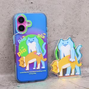 May include: A blue phone case with a cartoon cat design. The design features a light blue cat on top of a yellow cat, with the text "enduring the merciless beating of life every day". A matching cat charm is also present.