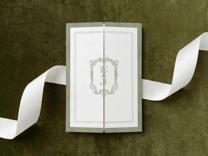 May include: A rectangular gatefold invitation card featuring a white center panel with a sage green ornate frame and the letters E & J in the middle. The card has sage green outer panels and is accented by a long, flowing white satin ribbon.