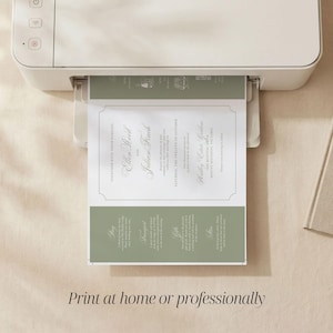 May include: A white home printer outputting a wedding invitation card featuring sage green accents and white text. The invitation displays the names Ellen Reed and Julian Finch, along with event details, framed by a thin border on a white background.