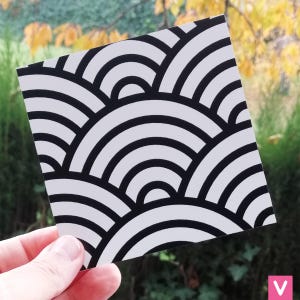 Op de afbeelding: Zwart-wit geometrisch patroon met overlappende halve cirkels. Het patroon wordt herhaald over de hele afbeelding.