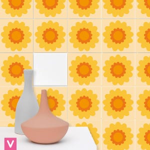 Op de afbeelding: Een retro bloemenpatroon in geel, oranje en crème. Twee decoratieve vazen in grijs en perzik staan voor de tegels. De tegels hebben een herhalend patroon van gestileerde bloemen.