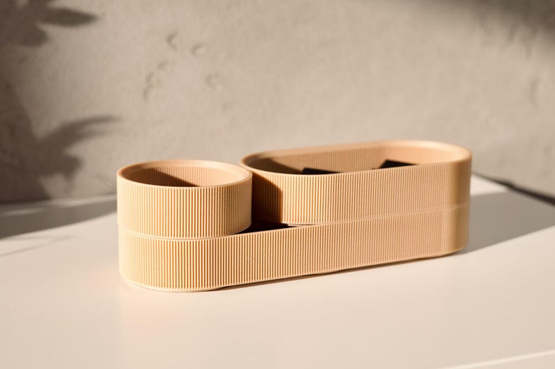 May include: A set of three beige, cylindrical containers with a ribbed texture. The containers are stacked on top of each other, with the largest container at the bottom and the smallest container at the top.