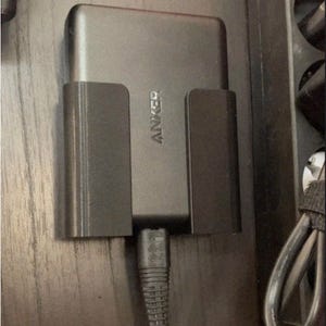 May include: A black Anker power adapter with a 3D-printed holder. The adapter is connected to a black cable. The text "VIRTUAL REALITY 3D" and a star rating are visible.