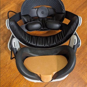 Puede incluir: Un casco de realidad virtual desmontado con componentes en blanco y negro. El casco presenta una diadema negra, una almohadilla facial y un ocular. El texto "VIRTUAL REALITY 3D" es visible.