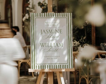 Puede incluir: Un caballete de madera exhibe un letrero de bienvenida de boda. El letrero presenta los nombres de Jasmine Johnson y William Smith, con la fecha del 28 de julio de 2023. El letrero tiene un fondo blanco con bordes y texto a rayas verdes.
