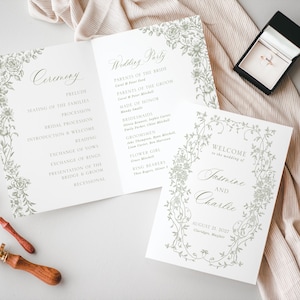 Peut inclure: Ensemble de papeterie de mariage comprenant un programme de cérémonie, les détails du cortège nuptial et une carte de bienvenue. Les cartes sont blanches avec des motifs floraux et une écriture élégante. Une boîte à bagues, des alliances et un sceau de cire sont également présents.