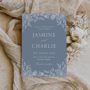 Peut inclure: Une invitation de mariage bleu clair avec des motifs floraux. Le texte "JASMINE et CHARLIE" est mis en évidence, avec la date "21 AOÛT 2027". On peut également lire "Vous êtes cordialement invités" et "Réception à suivre".