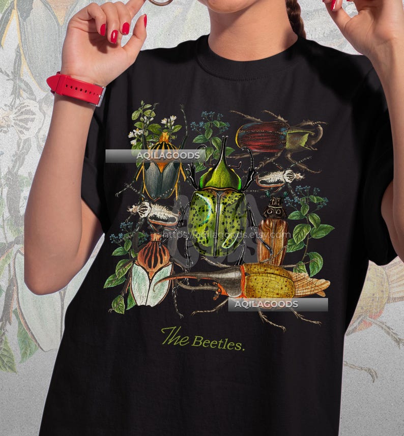 May include: Black t-shirt featuring a detailed illustration of various beetles in shades of green, brown, and yellow, surrounded by botanical elements. The text "The Beetles" is printed at the bottom. The brand name "AQILAGOODS" is also visible.