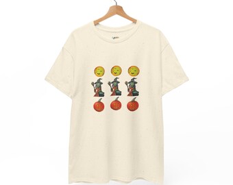 Op de afbeelding: Een crèmekleurig t-shirt met korte mouwen en een gespikkelde textuur. De voorkant is voorzien van een grafische print in drie rijen: drie gele manen, drie groene heksen met bezems en ketels, en drie oranje pompoenen met gezichten.