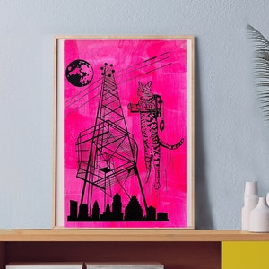 May include: A yellow cabinet with a single sliding door and a shelf. The cabinet is sitting on a wooden floor. A framed print of a pink cityscape with a cat climbing a tower is hanging on the wall above the cabinet. A potted plant is on the shelf.