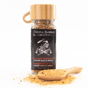 May include: A glass spice jar with a bamboo lid and a wooden spoon filled with a sweet and spicy blend. The jar's label features a Native American illustration and text that reads "TOMAHAWK BLEND SWEET-SALTY & SPICY". The jar contains 2.65 Oz of spice.