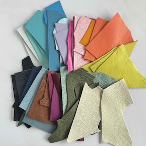 May include: Assortment of leather offcuts in various colours, including blue, green, purple, orange, yellow, pink, and brown. The leather pieces are cut into different shapes and sizes.