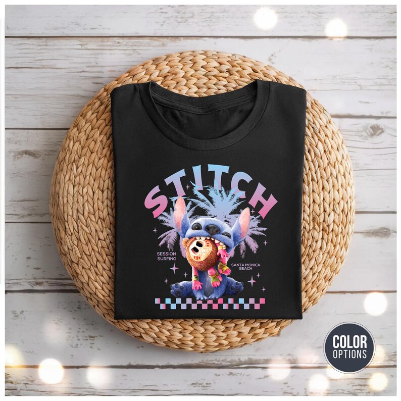 Może przedstawiać: Czarny t-shirt z kresk&oacute;wkową ilustracją Stitcha, ze słowem "STITCH" w czcionce gradientowej. Stitch trzyma kokos. Koszulka zawiera r&oacute;wnież tekst "SESSION SURFING" i "SANTA MONICA BEACH".