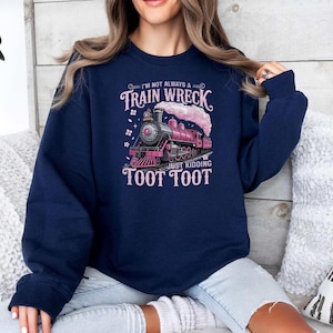 May include: Navy blue sweatshirt with a pink train graphic and the text "I'm not always a train wreck just kidding toot toot". The graphic features a pink train with a cloud of pink smoke.