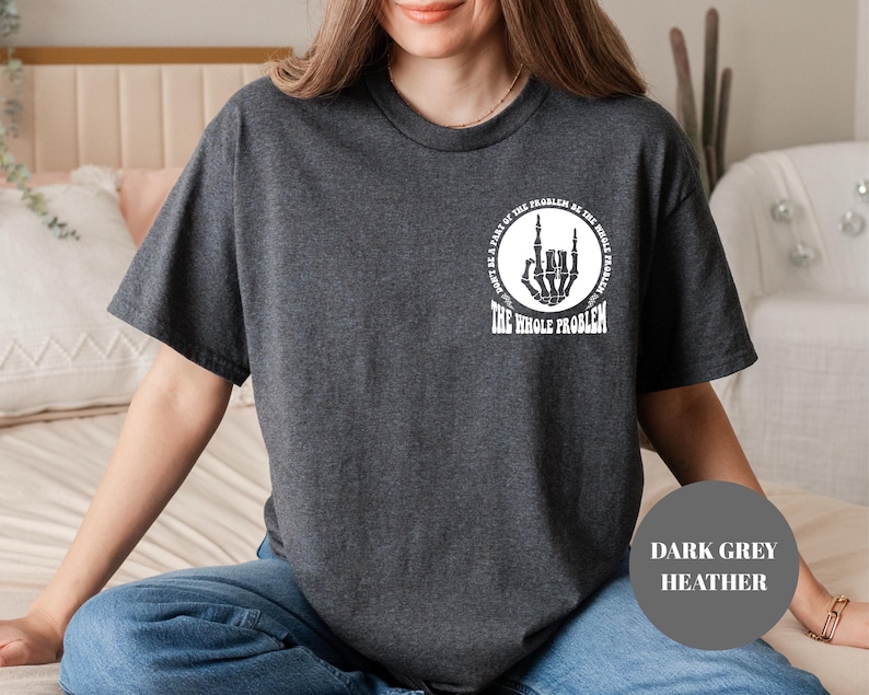 T-shirt featuring a front chest circle design with a skeleton hand and the words “The Whole Problem” surrounding it; the back showcases a large statement reading “Don’t Be a Part of the Problem, Be the Whole Problem” in bold font, with graphic accents like lightning bolts, skulls, and checkered flags. A rebellious and fun shirt for those with an edgy sense of humor — perfect as a gift for bold women or teens with attitude.