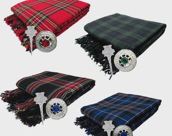 May include: Four folded tartan wool scarves in red, green, black, and blue, each with a matching kilt pin and a decorative brooch. The scarves have fringed edges and are arranged on a light gray background.