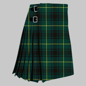 Op de afbeelding: Een groene en zwarte geruite kilt met gele accentlijnen. De kilt heeft een geplooid ontwerp en twee zilveren gespen. Het traditionele Schotse kledingstuk is gemaakt van geweven stof.