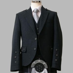 Puede incluir: Chaqueta de lana gris oscuro con chaleco a juego y camisa blanca. La chaqueta tiene solapa de muesca, tres botones y botones decorativos en las mangas. Se ve un kilt escocés tradicional.