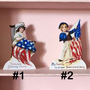 May include: Four vintage patriotic paper cutouts featuring children in red, white, and blue clothing holding American flags and singing. The cutouts are labeled with numbers 1 through 4 and patriotic phrases.