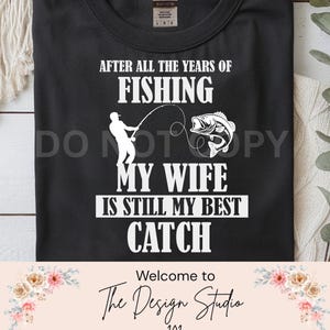 May include: Black t-shirt with white text and graphic. The text reads "AFTER ALL THE YEARS OF FISHING, MY WIFE IS STILL MY BEST CATCH." A graphic of a fisherman and a fish is also included.