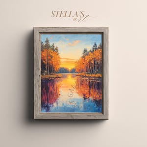 Op de afbeelding: Een ingelijst landschapsschilderij toont een meer bij zonsondergang. Het kunstwerk gebruikt een levendig kleurenpalet van oranje, geel en blauw, met reflecties in het water. De lijst is van lichtgrijs hout. De tekst "STELLA'S art" staat rechtsboven.