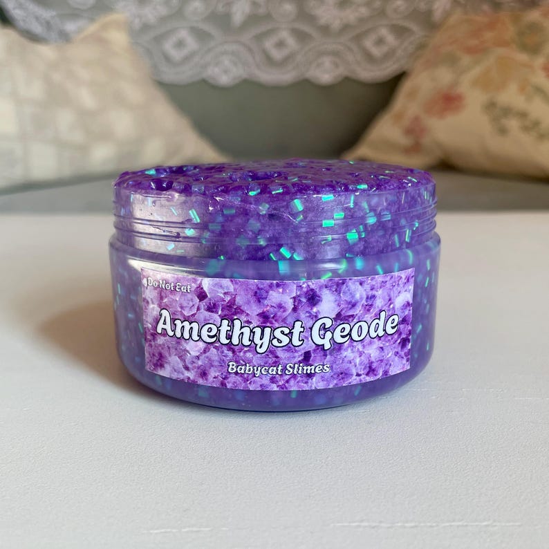 A container labeled "Amethyst Geode by Babycat Slimes" is overflowing with a shimmering purple bingsu slime.