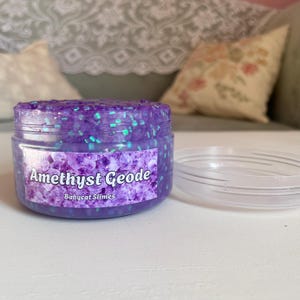 A container labeled "Amethyst Geode by Babycat Slimes" is overflowing with a shimmering purple bingsu slime.