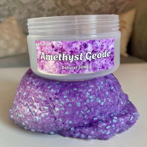 A container labeled "Amethyst Geode by Babycat Slimes" is overflowing with a shimmering purple bingsu slime.