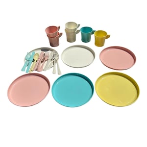 May include: A colorful picnic set featuring plates, cups, and cutlery. The set includes pink, white, blue, and yellow plates, along with matching cups and a variety of forks, knives, and spoons. Perfect for outdoor dining.