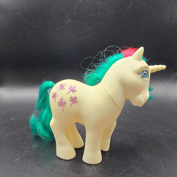 My Little Pony G1 Gusty Unicornio, color crema, azul verdoso, rosa, con purpurina y hojas, de Hasbro, año 1984.